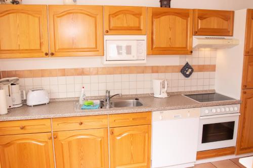 a kitchen with wooden cabinets and a sink at Reet und Meer Beckerwitz in Hohenkirchen