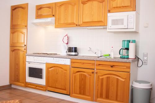 a kitchen with wooden cabinets and a white stove top oven at Reet und Meer Beckerwitz in Hohenkirchen