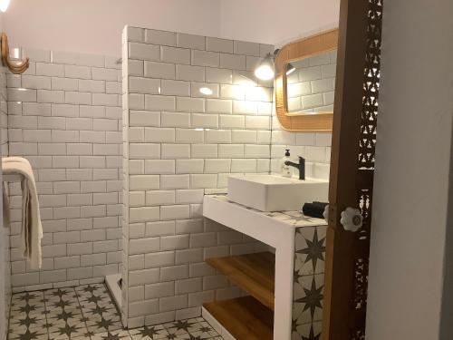 een witte badkamer met een wastafel en een spiegel bij Kasbah Andaluz guest house in Chiclana de la Frontera