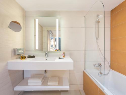 y baño con lavabo, espejo y bañera. en Mercure Béziers en Béziers