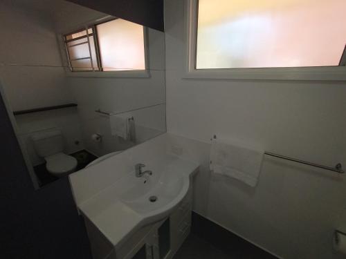 a white bathroom with a sink and a toilet at Aspley Sunset Motel in Brisbane