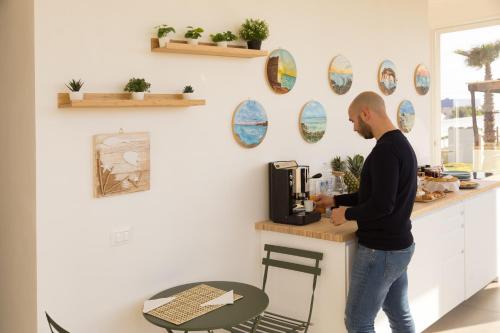 a man standing at a counter with a coffee maker at Marezè in Punta Secca