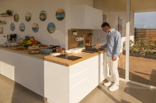 a man standing at a counter in a kitchen at Marezè in Punta Secca