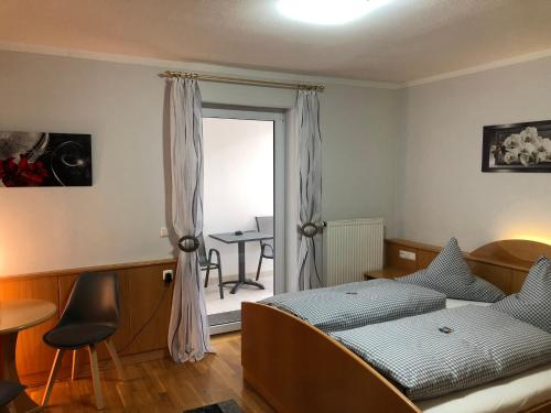 a bedroom with a bed and a table and a window at Hotel u. Restaurant Goldener Greifen in Donauwörth