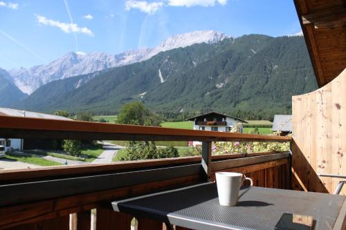 a coffee cup on a table on a balcony with mountains at Zauscherhof in Wildermieming