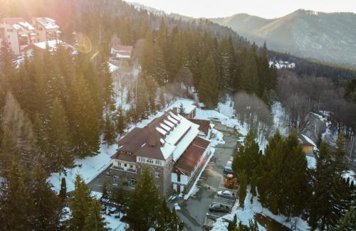 a building in the middle of a snow covered forest at Hotel Bucegi Portile Regatului in Paraul Rece