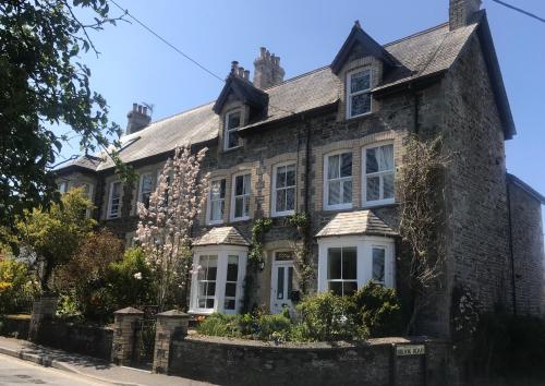 an old stone house with white windows and flowers at Brookdale House in Wadebridge