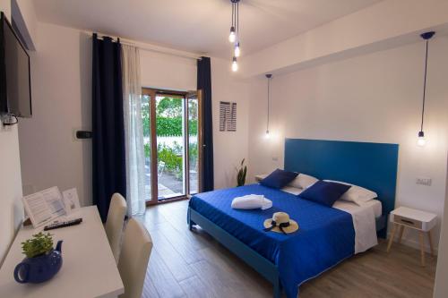 um quarto com uma cama azul, uma mesa e cadeiras em Maison Ligea em Sorrento