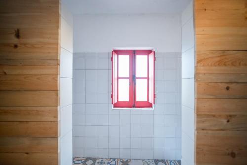 a red window in a bathroom with white tiles at Monte Gois Country House e Spa in Curvatos