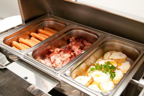 two trays of food in a refrigerator with carrots and meat at Hotel u Ledu in Velké Popovice