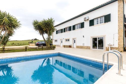 a villa with a swimming pool in front of a house at Quinta do Selão in Cabanas de Torres