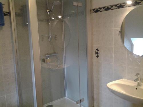 um chuveiro com uma porta de vidro ao lado de um lavatório em Chambre d'Hôtes La Maison de Barrouze em Salers