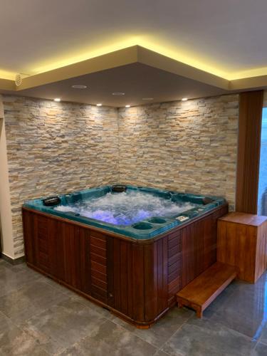a large hot tub in a room with a stone wall at The Jakuzzi Room Miskolctapolca in Miskolc