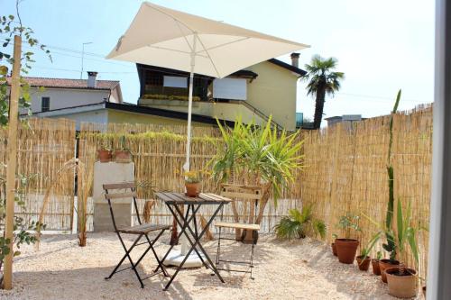 a table and chairs with an umbrella in front of a fence at Pathos Guest House in Quarto dʼAltino