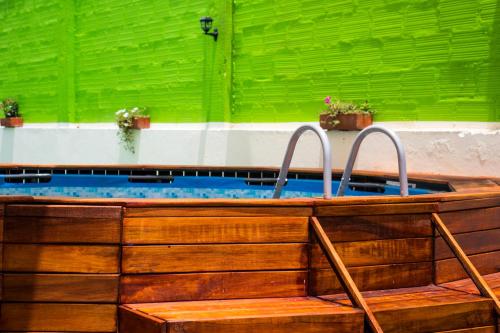 a wooden bath tub with two handles in a green wall at Casa Lilí Guaduas in Guaduas