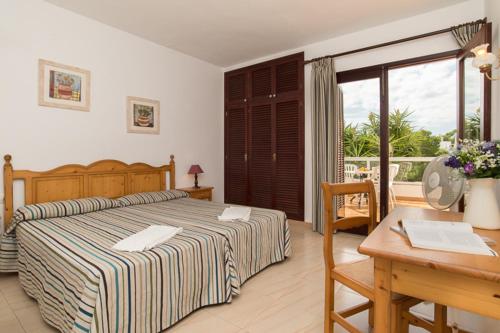 - une chambre avec un lit, un bureau et une table dans l'établissement Apartamento Playa Dor 14, à Cala d´Or