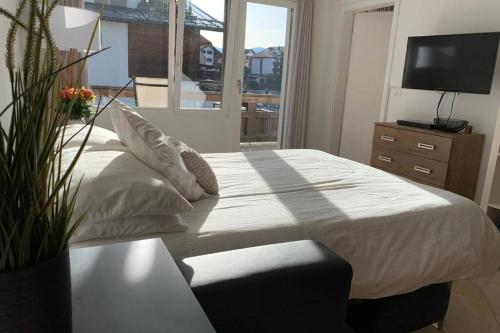1 dormitorio con 1 cama, TV y ventana en Apartment near Laax Lake, en Laax
