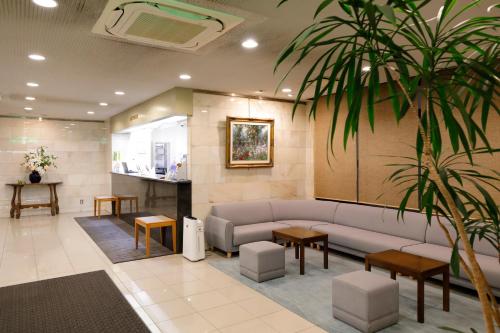 a waiting room with a couch and a palm tree at Kawasaki Central Hotel in Kawasaki