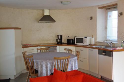 een keuken met een tafel met stoelen en een magnetron bij Gîtes du Manoir de Goandour in Crozon