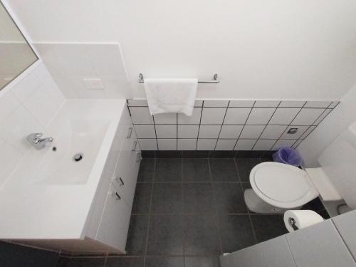a white bathroom with a toilet and a sink at Aspley Sunset Motel in Brisbane