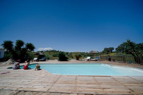 a group of people sitting around a swimming pool at Monte Gois Country House e Spa in Curvatos