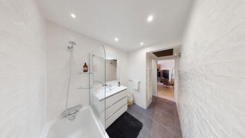 une salle de bain blanche avec une baignoire et un lavabo dans l'établissement La Bonne Brise - Superbe loft avec terrasse à 2 minutes de la plage, à Marseille