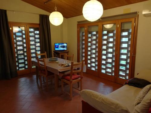 ein Esszimmer mit einem Tisch, Stühlen und einem TV in der Unterkunft Il Fienile della Farnia in Pistoia