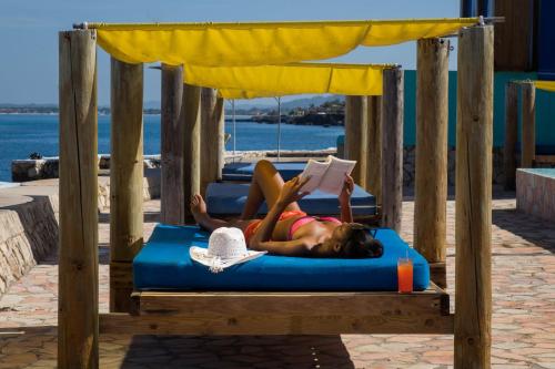 a woman laying on a bed reading a book at Samsara Cliff Resort in Negril