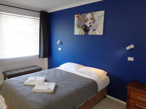 a blue bedroom with a bed with towels on it at Aspley Sunset Motel in Brisbane