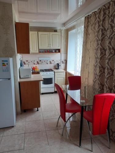 ザポリージャにあるDeluxe Apartment - Sobornyi 68の小さなキッチン(テーブル、赤い椅子付)