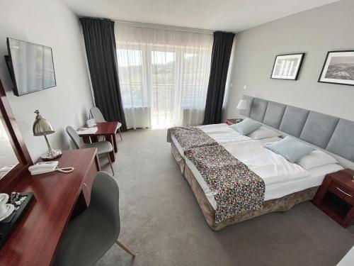a hotel room with a large bed and a desk at Hotel Srebrna Góra in Srebrna Góra