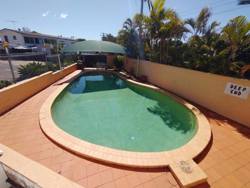 a large swimming pool on a patio with an umbrella at Aspley Sunset Motel in Brisbane