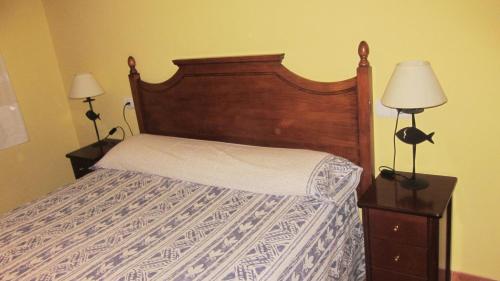 a bedroom with a bed with a wooden headboard and two lamps at Apartaments la Fabrica in Horta de San Joan
