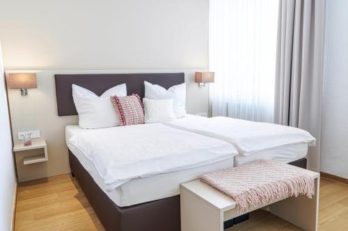 1 dormitorio con 2 camas con sábanas y almohadas blancas en Tante ALMA's Kölner Hotel en Colonia