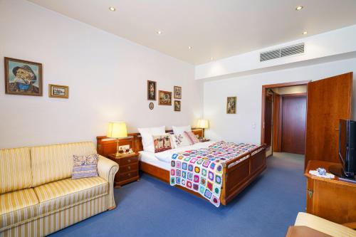 a bedroom with a bed and a couch and a tv at Tante ALMA's Kölner Hotel in Cologne