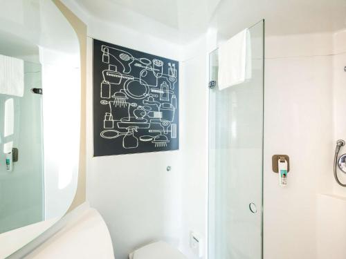 a bathroom with a black and white painting on the wall at ibis London Elstree Borehamwood in Borehamwood