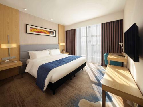 a hotel room with a bed and a television at ibis Styles Changsha Intl Exhibition Ctr in Huangxing