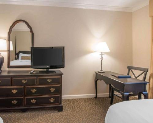 a hotel room with a desk with a television and a bedroom at The Century House, an Ascend Collection Hotel in Latham