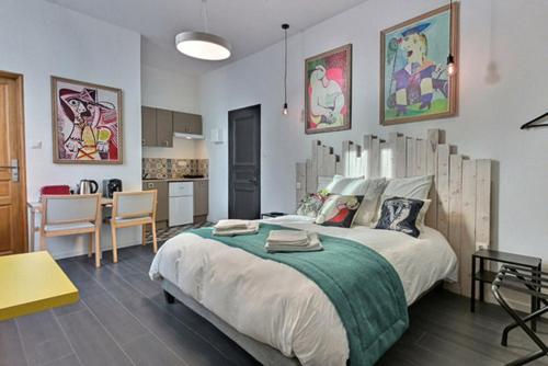 a bedroom with a large bed and a kitchen at Les Appartements Fénelon in Le Cateau