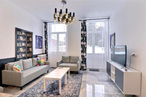 a living room with a couch and a tv at Les Appartements Fénelon in Le Cateau