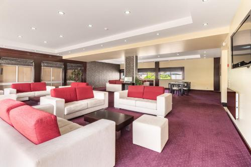 a living room with white furniture and red pillows at Hotel Colmeia in Monte Real