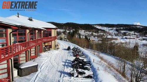 a building with a line of snowmobiles parked in the snow at Hattfjelldal Hotell in Hattfjelldal