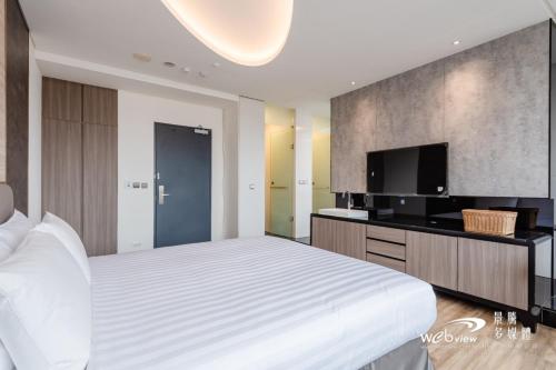 a bedroom with a large bed and a flat screen tv at 玩行旅台北分館 in Taipei