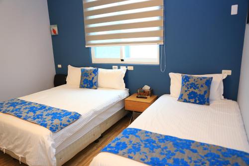 two beds in a room with blue walls and a window at 500Km Home in Hualien City