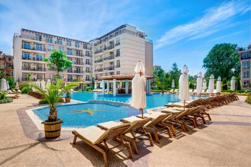 una piscina in un hotel con sedie a sdraio e ombrelloni di Dawn Park Complex a Sunny Beach