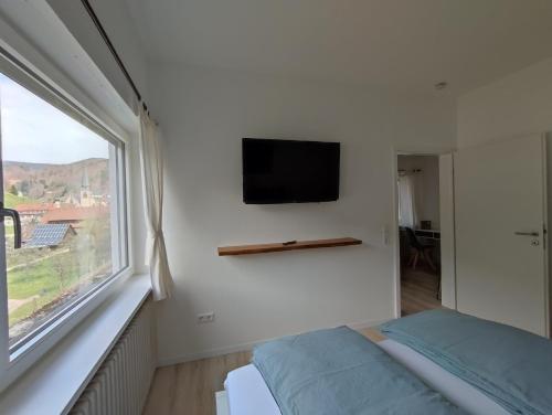 1 dormitorio con ventana y TV en la pared en Steepleview House en Bad Peterstal-Griesbach