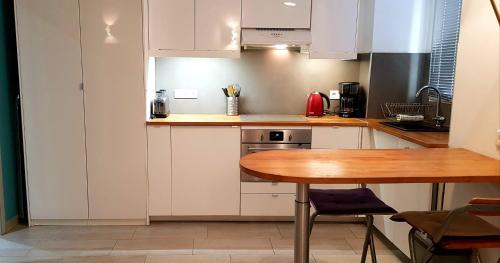 a kitchen with white cabinets and a wooden table at Studio centre ville in Ajaccio