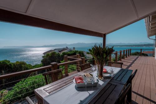 a table on a deck with a view of the ocean at Oceanfront bungalow 3 br/2 ba, Wifi Fireplace: Guppy Huys in De Kelders