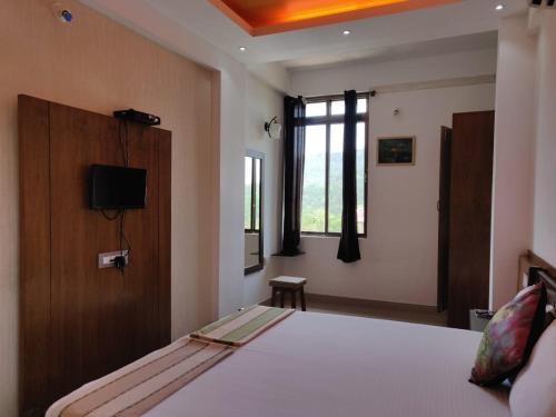 a bedroom with a bed and a tv in it at Hotel Mudra Midtown in Kalasa