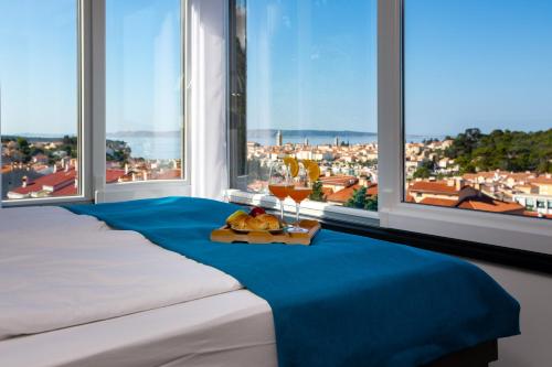 a bed with a tray of food and drinks in a room with windows at Villa Venka in Rab